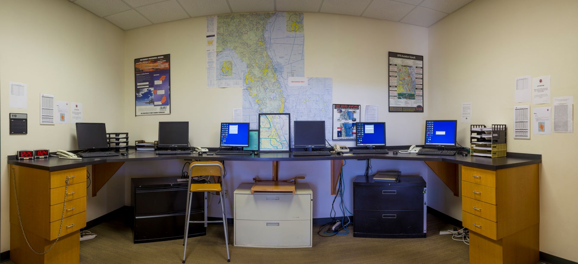 Flight planning room with multiple computer stations and aviation charts on the wall
